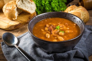 Domates soslu fasulye, pastırma ve siyah kasede sosis. Seçici odak.