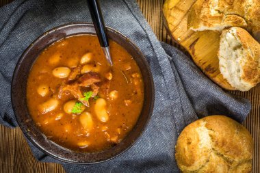 Domates soslu fasulye, pastırma ve siyah kasede sosis. Seçici odak.