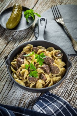 İtalyan makarna kabukları ve biftek sosu ahşap masada dökme demir tavada..