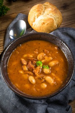 Domates soslu fasulye, pastırma ve siyah kasede sosis. Seçici odak.