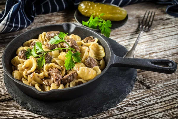Italian pasta shells with beef sauce in cast iron pan on wooden table.