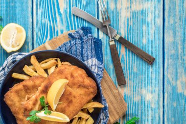 Tabakta patates kızartması olan kızarmış morina balığı. Üst görünüm.