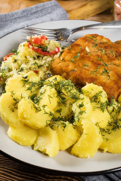 Breaded fish with potato and salad of sauerkraut for dinner. Selective focus.