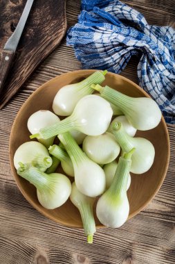 Ahşap bir kapta beyaz genç soğan.