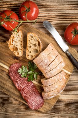 İtalyan ciabatta ekmeği Dilim salam ile Ahşap doğrama tahtası üzerinde kesilmiş.