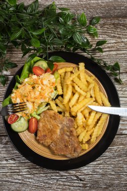 Geleneksel Polonya yemeği: kızarmış domuz pirzolası, patates kızartması ve salata ile servis edilir.. 