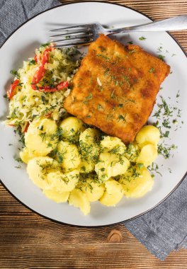 Akşam yemeğinde patates ve lahana turşusu salatası ile haşlanmış balık. Seçici odak.