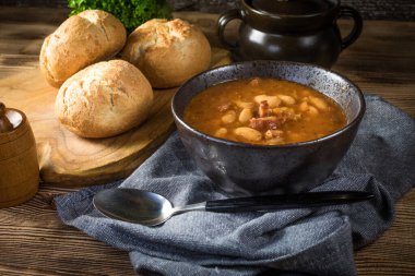 Domates soslu fasulye, pastırma ve siyah kasede sosis. Seçici odak.