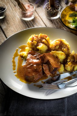 Haşlanmış patates ve salatalık salatasıyla servis edilen kendi soslu haşlanmış domuz boynu. Sığ alan derinliği.