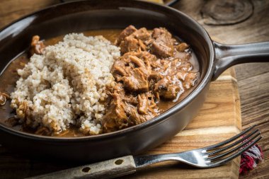 Bir tavada pişirilmiş etli arpa kabuğu çıkarılmış tane servis.