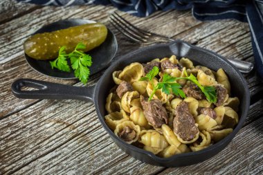 İtalyan makarna kabukları ve biftek sosu ahşap masada dökme demir tavada..