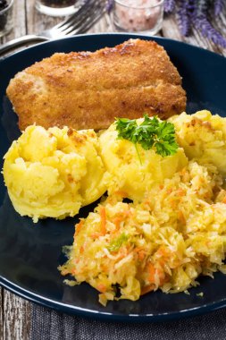 Haşlanmış patates ve sebze salatasıyla servis edilen kızarmış morina filetosu..