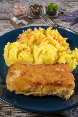 Haşlanmış patates ve sebze salatasıyla servis edilen kızarmış morina filetosu..