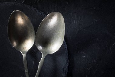 Koyu renkli tezgahta birkaç gümüş kaşık..