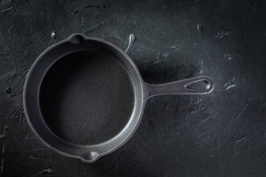 Siyah arka planda küçük bir dökme demir tava..