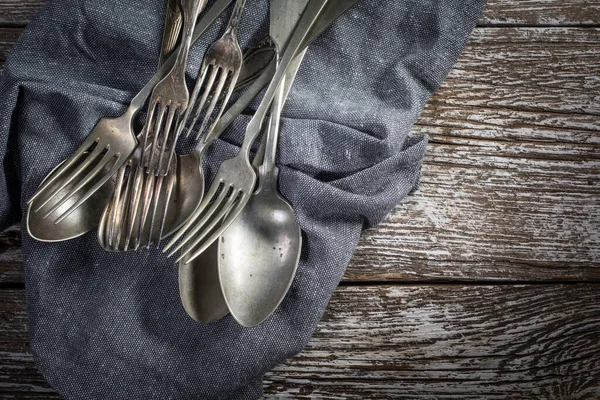 A few old silver spoons and forks. on a wooden countertop.