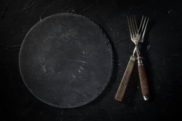 Несколько старых столовых приборов на темной столешнице
.