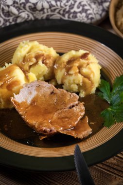 Kendi sosunda haşlanmış patates ve kızarmış lahanayla servis edilen haşlanmış domuz boynu. Sığ alan derinliği.