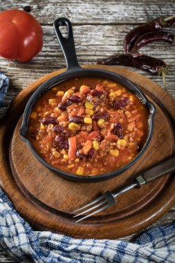 Ahşap arka planda kızartma tavasında Chili con carne. Seçici odak.
