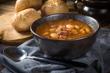 Domates soslu fasulye, pastırma ve siyah kasede sosis. Seçici odak.