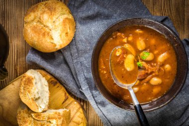 Domates soslu fasulye, pastırma ve siyah kasede sosis. Seçici odak.