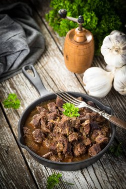 Dökme demir tavada sığır güveci, ahşap arka plan. Sığ alan derinliği.