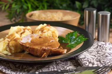 Kendi sosunda haşlanmış patates ve kızarmış lahanayla servis edilen haşlanmış domuz boynu. Sığ alan derinliği.