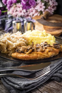 Mantarlı domuz pirzolası, haşlanmış lahana ve patates püresi ile servis edilir..