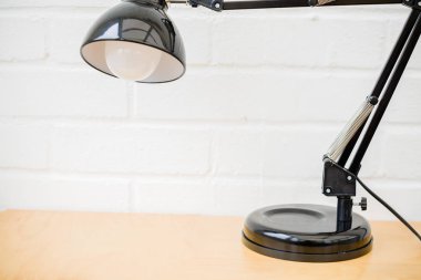 Anglepoise lamba. Beyaz tuğla arka plan ile ahşap masa retro masa üstü siyah ışık