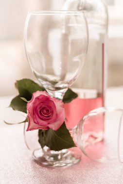 İki Şarap kadehi yarım tam önünde duran bir döşeme boş şişe kırmızı ya da gül şarap parlak yanan Günışığı arka plan ile güzel romantik gül