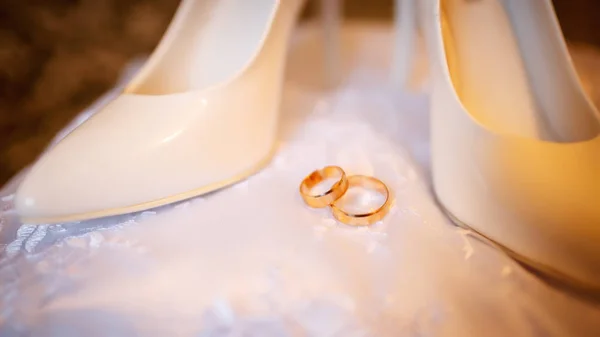 Sapatos de casamento e anéis em pé no travesseiro branco — Fotografia de Stock