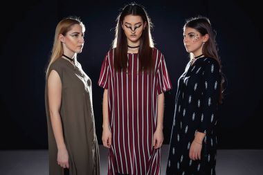 Üç benzersiz modelleri ile sıradışı bir makyaj ve özgün giysili bir podyum üzerinde poz