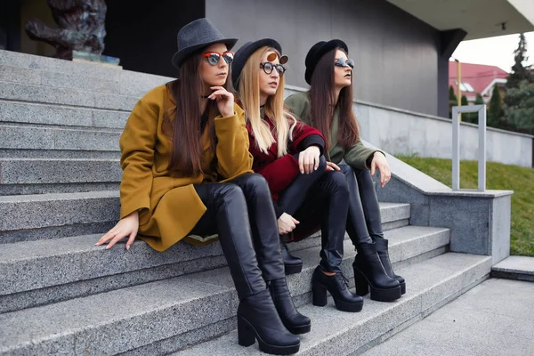 Стильные девушки с необычным макияжем в модных пальто, шарфах, шляпах и кожаных туфлях на лестнице к камбузу — стоковое фото