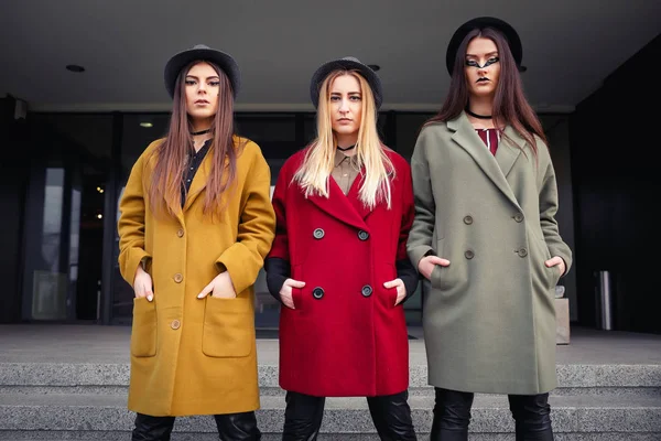 Trendy kat, eşarplar, şapka ve deri ayakkabı mutfak için merdivenlerde alışılmadık makyaj ile şık kızlar