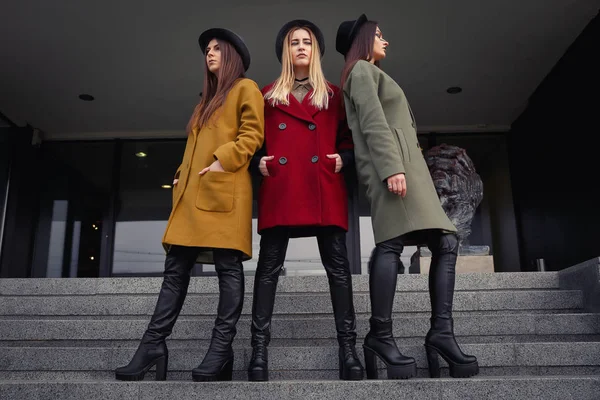 Trendy kat, eşarplar, şapka ve deri ayakkabı mutfak için merdivenlerde alışılmadık makyaj ile şık kızlar