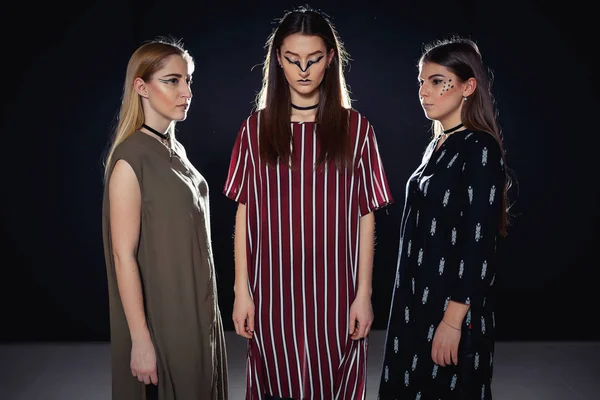 Üç benzersiz modelleri ile sıradışı bir makyaj ve özgün giysili bir podyum üzerinde poz