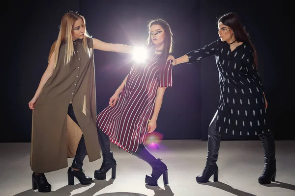 Üç benzersiz modelleri ile sıradışı bir makyaj ve özgün giysili bir podyum üzerinde poz
