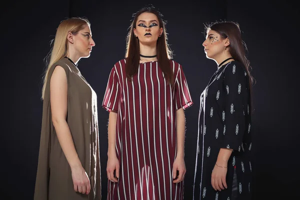 Üç benzersiz modelleri ile sıradışı bir makyaj ve özgün giysili bir podyum üzerinde poz
