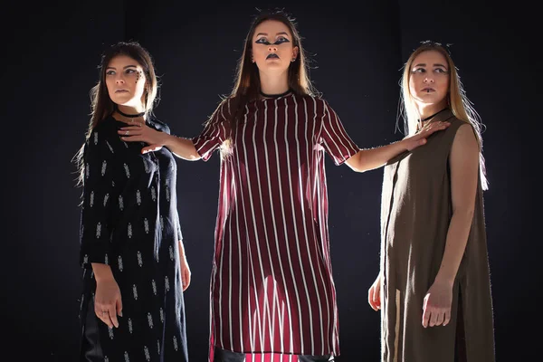 Üç benzersiz modelleri ile sıradışı bir makyaj ve özgün giysili bir podyum üzerinde poz