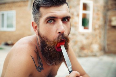 Bir adam şık bir saç modeli, uzun sakallı ve büyük bir zevk ile dövme karpuz yiyor