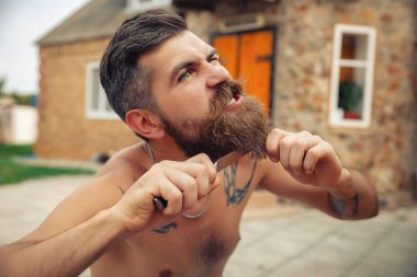 Bir adam şık bir saç modeli, uzun sakallı ve büyük bir zevk ile dövme karpuz yiyor