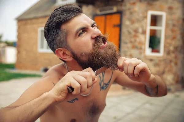 Bir adam şık bir saç modeli, uzun sakallı ve büyük bir zevk ile dövme karpuz yiyor