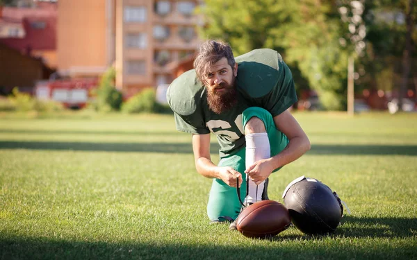 American football player in a green sport uniforms with black long beard trains on the football field