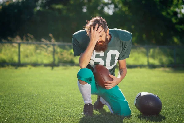 Amerikan futbolu oyuncusu yeşil bir spor futbol sahasına siyah uzun sakallı tren resmi