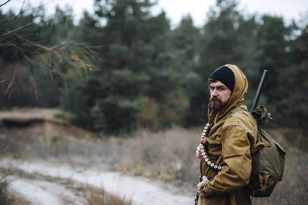 Skäggiga jägare med professionell utrustning promenader i skogen — Stockfoto