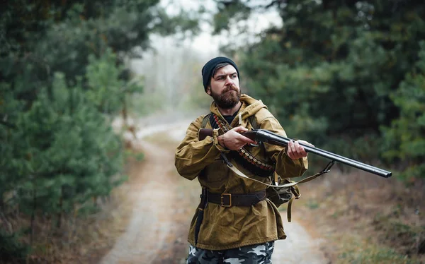 Bearded hunter with professional equipment walking in the woods — Stock Photo, Image