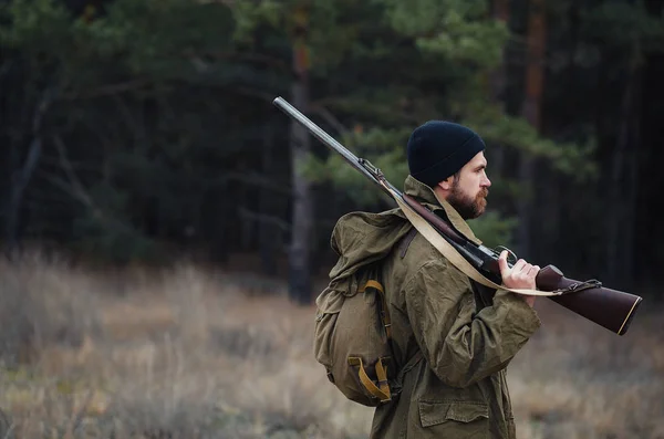 Cazador barbudo con equipo profesional caminando por el bosque — Foto de Stock