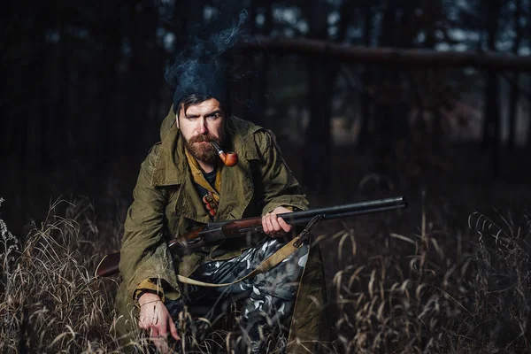 Bärtiger Jäger mit professioneller Ausrüstung im Wald unterwegs — Stockfoto