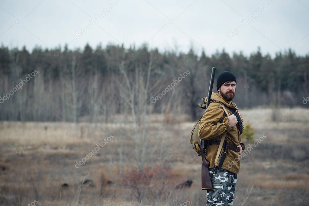 Bearded hunter with professional equipment walking in the woods