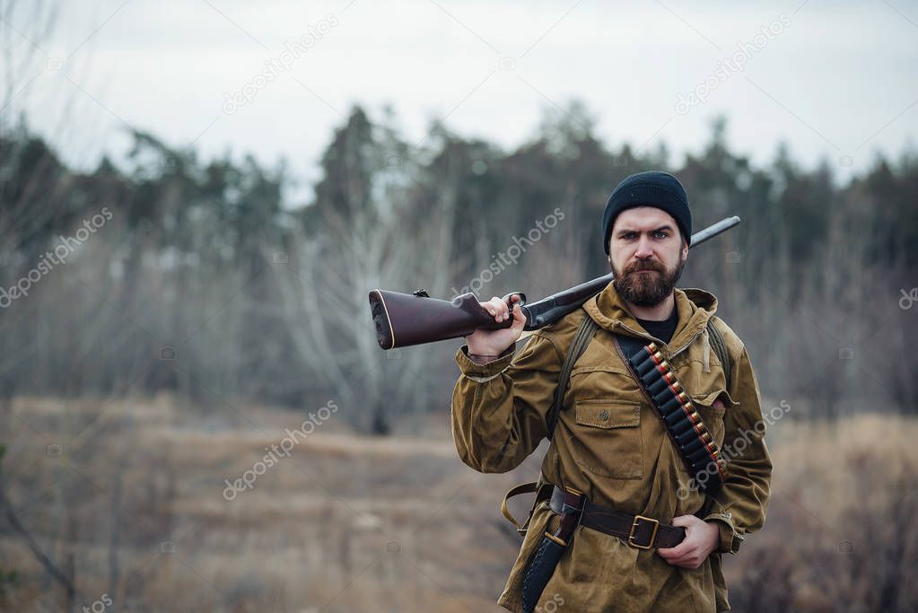 Bearded hunter with professional equipment walking in the woods